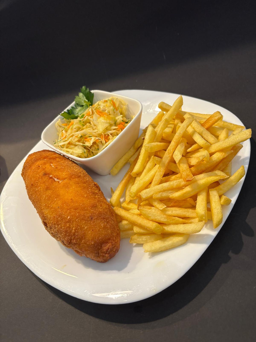 Panierowany kotlet z frytkami i surówką na białym talerzu w restauracji U Gawła